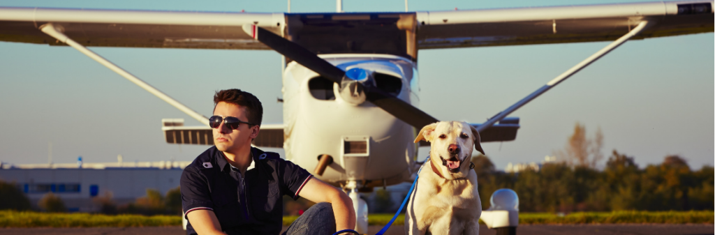 A dog and its owner in front of an airplane